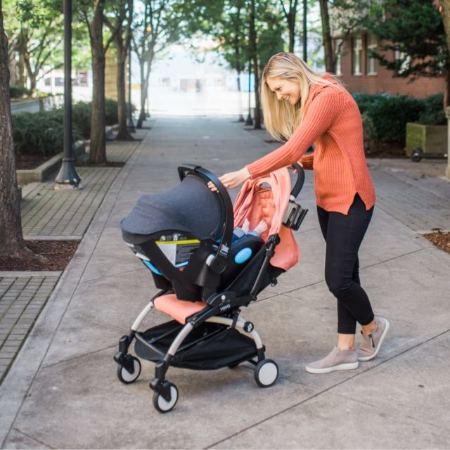 Mom pushing her baby in a Clek Liing infant car seat on a BABYZEN YOYO Stroller