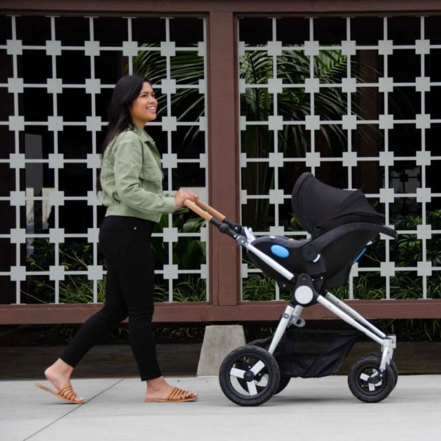 Mom pushing her baby in a Clek Liingo infant car seat on a Bumbleride Stroller