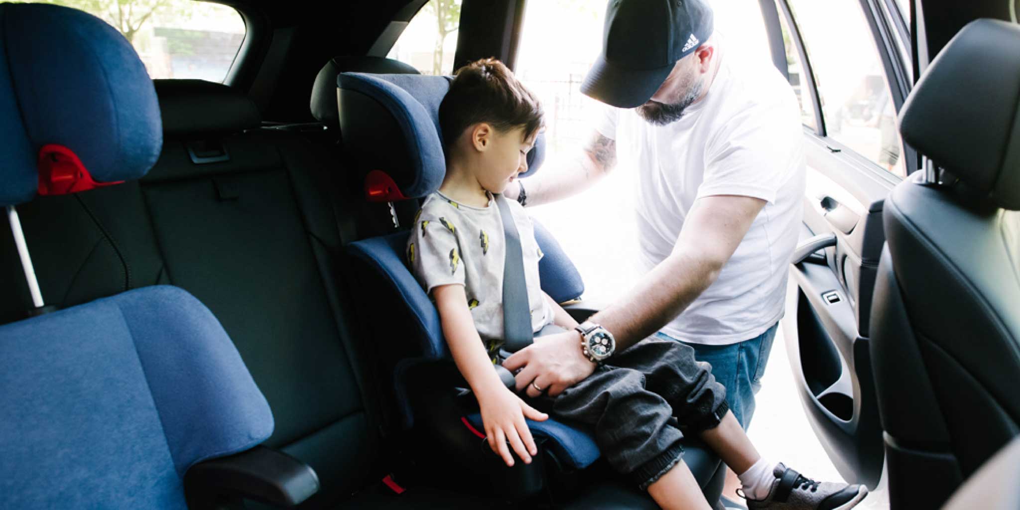 Father buckling his son into his Clek Oobr booster seat 