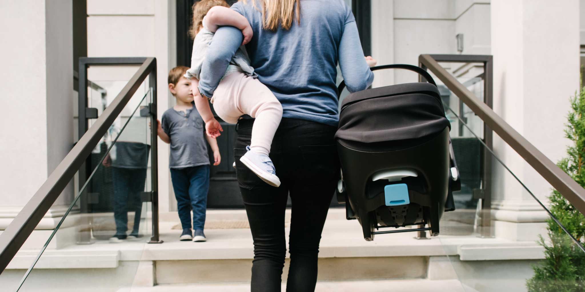 Mom carrying her baby and a Clek Liing infant car seat