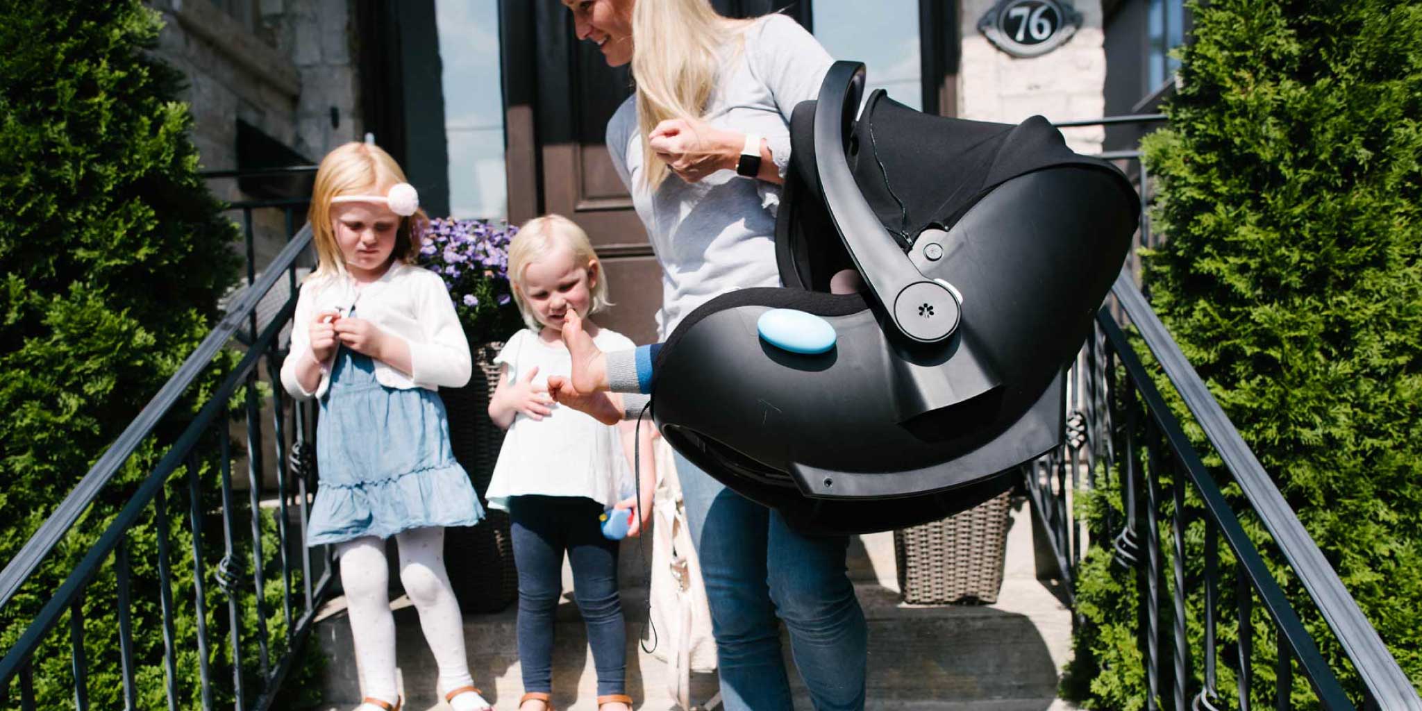 Mom carrying her baby and a Clek Liingo infant car seat