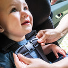 Child being secured in their Clek Foonf car seat buckling the chest clip all-groups