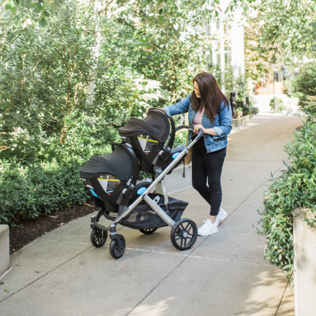 Mom pushing her baby in a Clek Liing infant car seat on an UPPAbaby Vista Stroller
