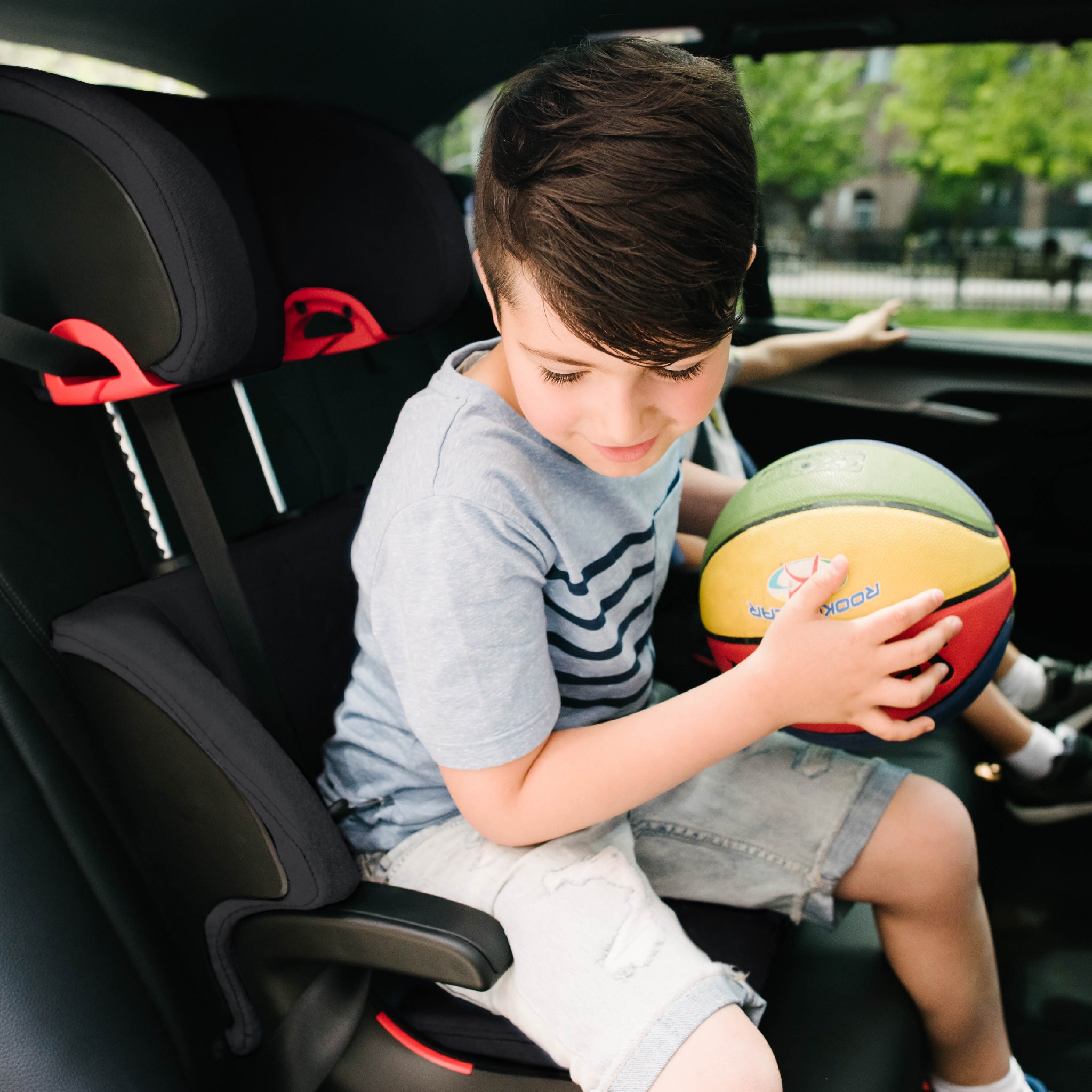 Child sitting in a car seat holding a basketball all-groups
