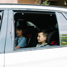 Two children sitting in a car riding in their Clek Oobrs  all-groups