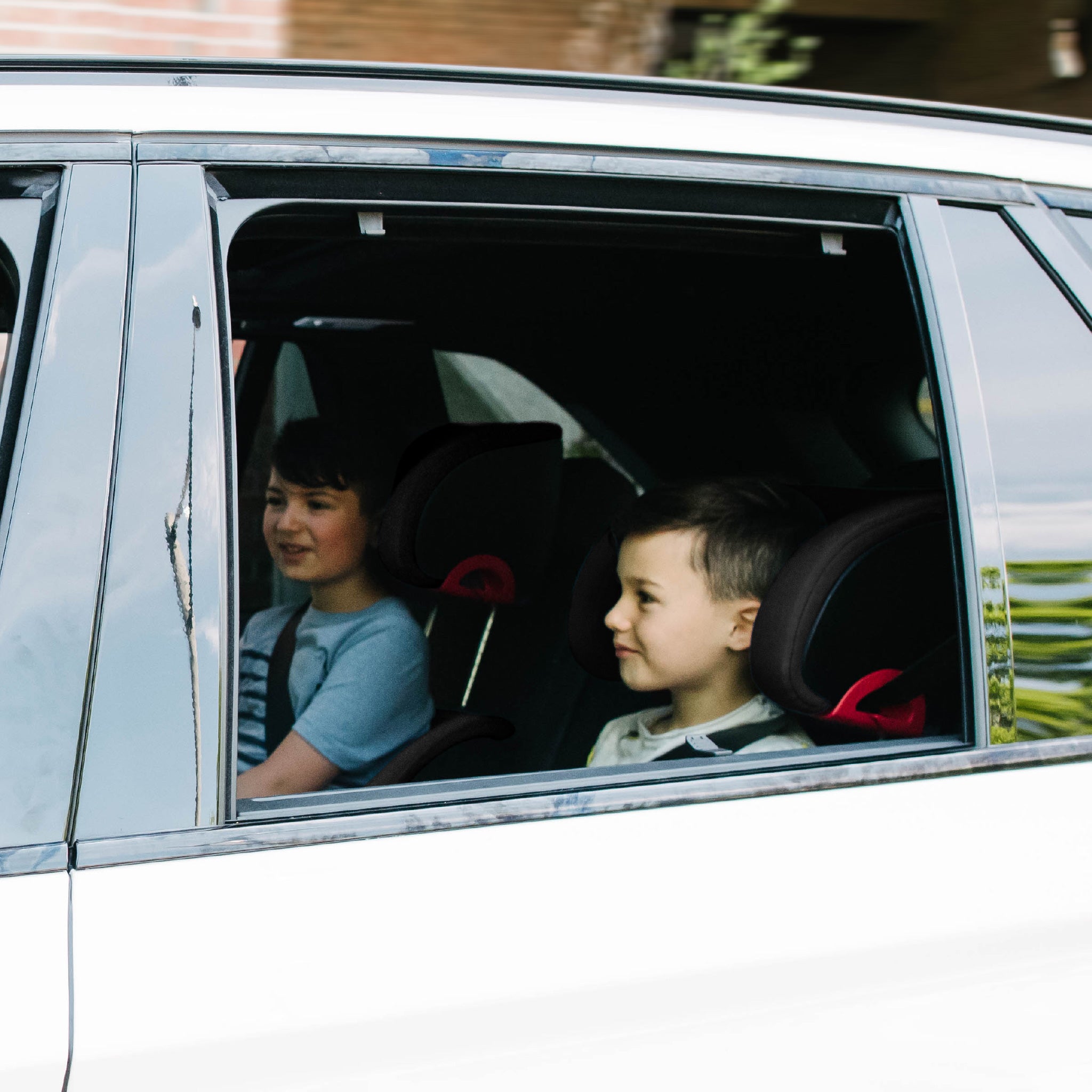 Two children sitting in a car riding in their Clek Oobrs  all-groups