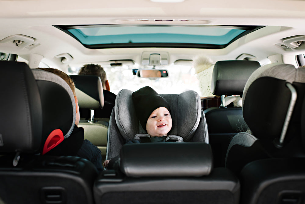 Child buckled in to his Clek convertible car seat in rear-facing position