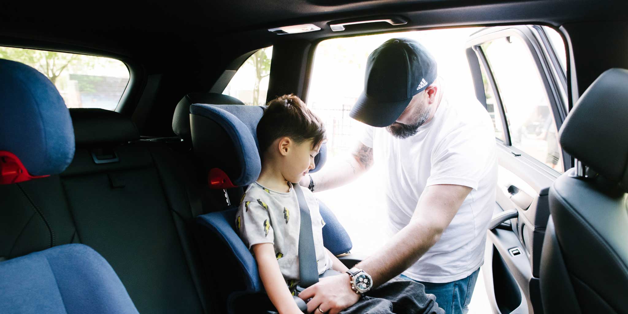 Dad buckling his son into a Clek Oobr booster seat