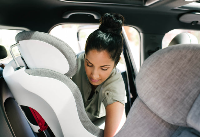 Woman installing a Clek Foonf convertible car seat